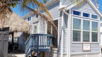 Enjoy a beachfront retreat with a unique architectural style, featuring a wooden deck and thatched roof structure.