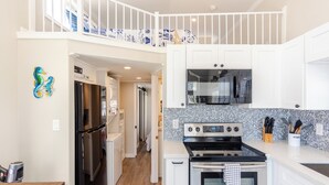 A modern kitchen with white cabinets, a stainless steel refrigerator, a black stove, and a microwave. - Little Piece of Paradise /w Kayaks, Private Dock and BBQ (Key Largo)