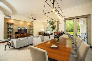 A modern living room with a dining area, a sofa, a TV, and a ceiling fan. - Bella Vista 7E, 3Bdr/3.5 Bth Condo (Playa Herradura)