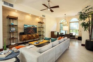Una sala de estar moderna con sofá, mesa de centro, televisor y elementos decorativos.