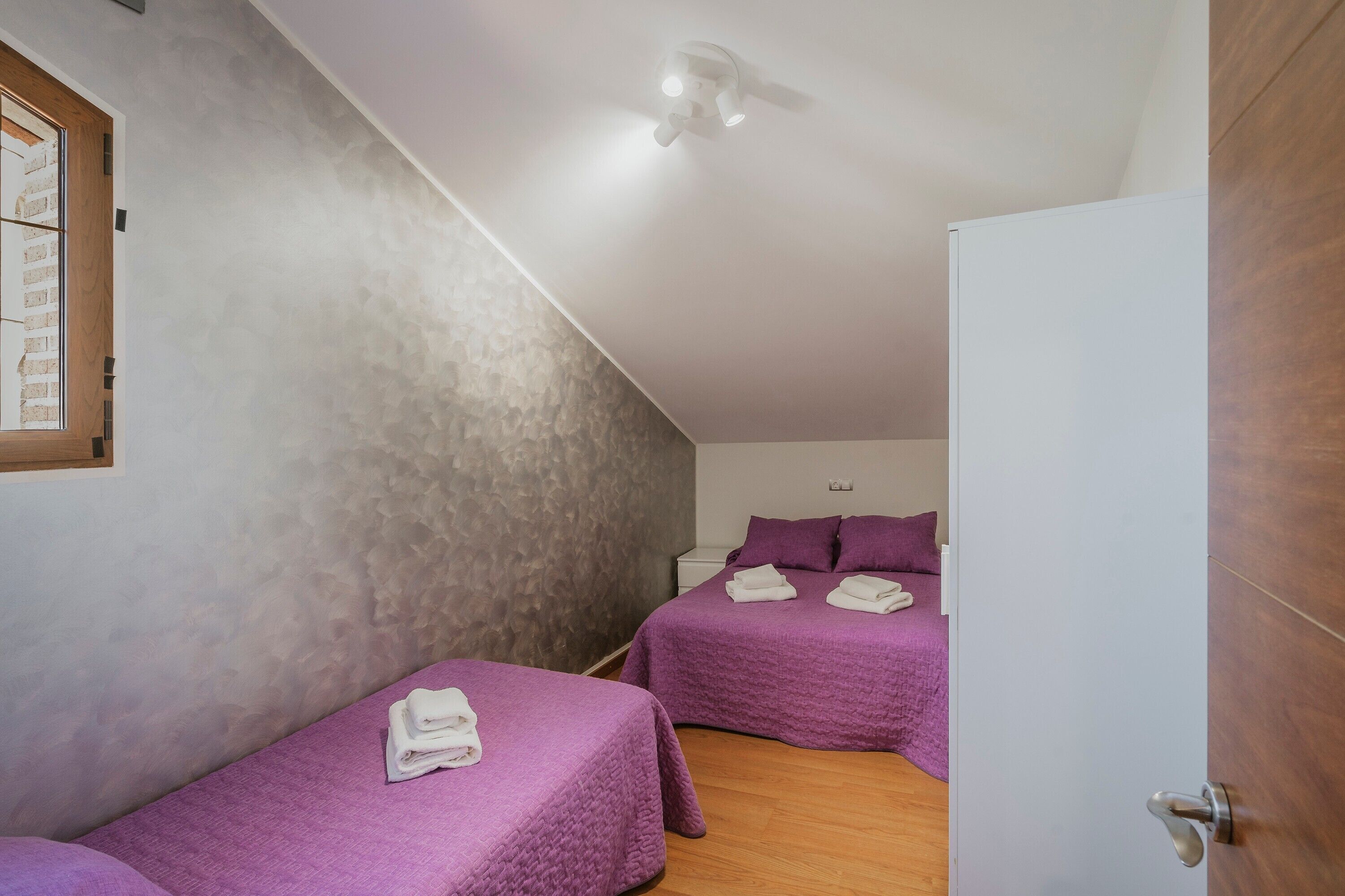 Un dormitorio con dos camas, un ventilador de techo y un armario blanco.