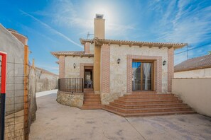 Una casita con techo de tejas, chimenea y una escalera que lleva a la entrada.