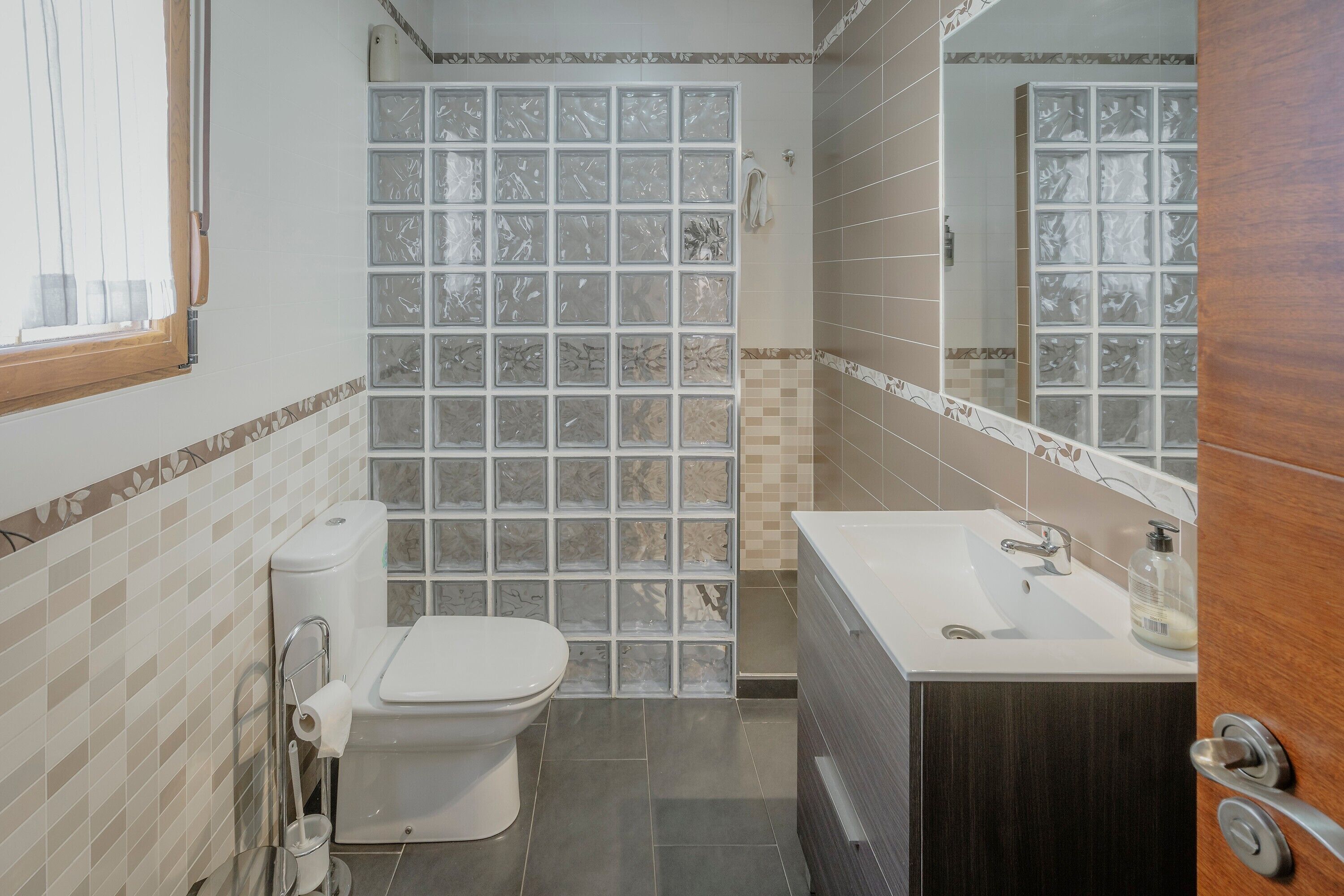 Un baño con inodoro, lavabo y zona de ducha.