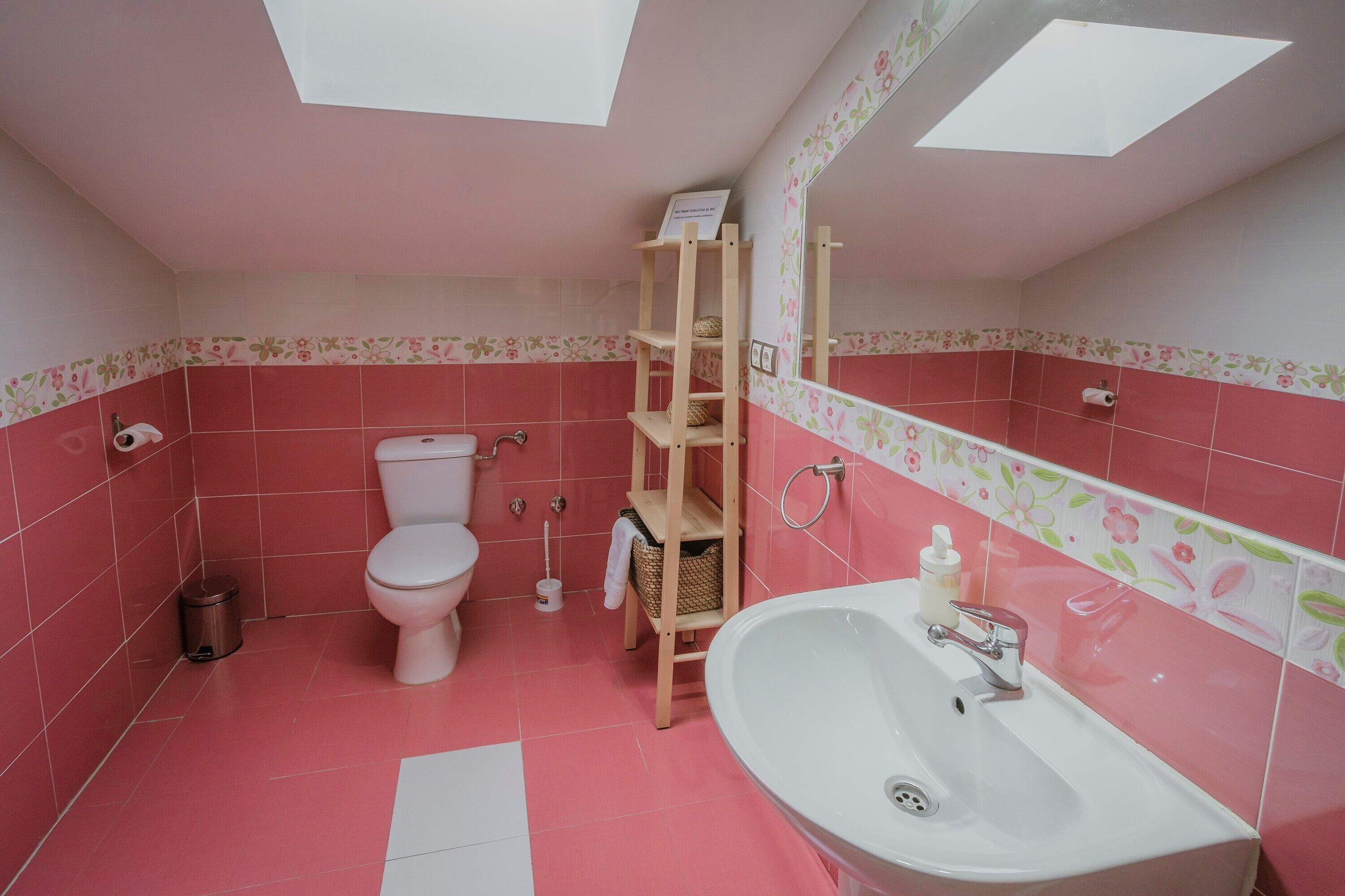 A bathroom with a toilet, sink, and a wooden shelf unit.