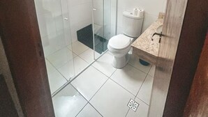 A bathroom with a glass-enclosed shower, a toilet, and a sink.