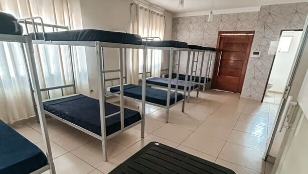 A dormitory room with bunk beds, a black table, and a tiled floor.