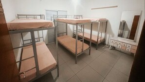 A dormitory room with bunk beds, a dresser, and a mirror.