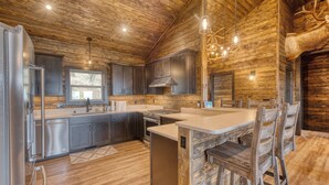 A rustic kitchen with wooden walls, a central island, and modern appliances. - Get away and relax at Elk Ridge, a modern lodge in the mountains of Ruidoso. (Ruidoso)