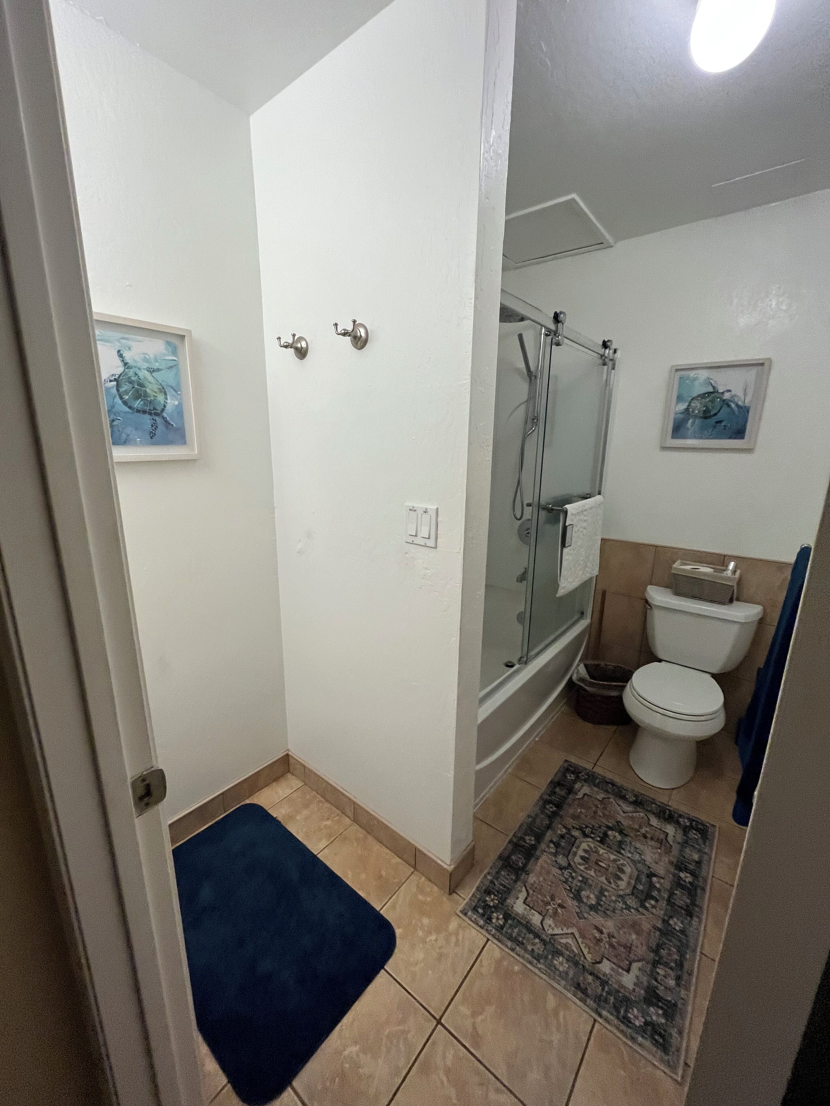 Un baño con ducha, inodoro y alfombra.