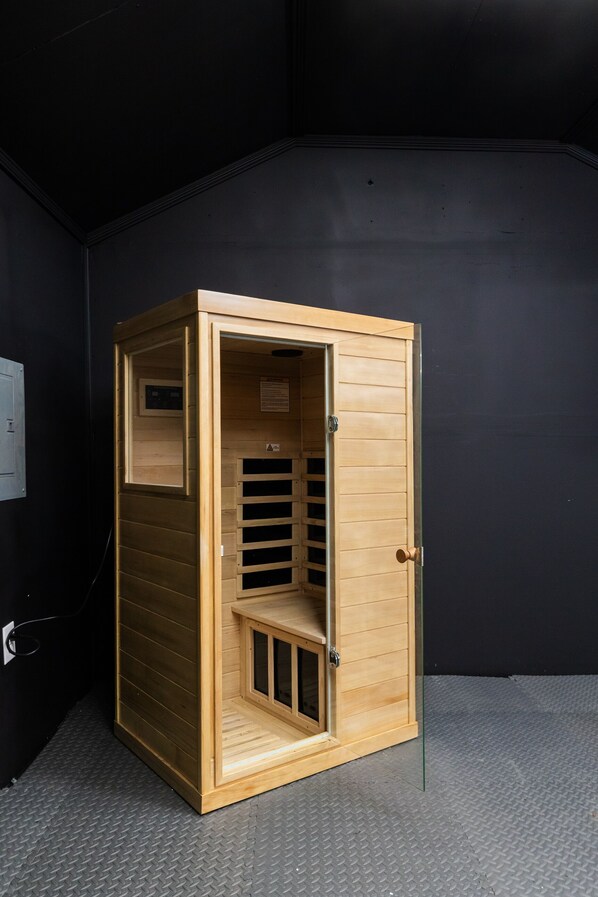 A wooden sauna with a door, a ventilation window, and a small enclosed area with a bench. - Perfect GSO Location; Hot Tub;Gym w/ Sauna;Playset (Greensboro)