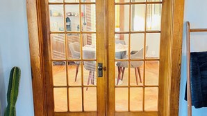 Una porta in legno con pannelli di vetro che dà accesso a una sala da pranzo con sedie e tavolo.