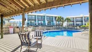 Eine Holzterrasse mit Pool, Liegestühlen und einem Schild mit Poolregeln.