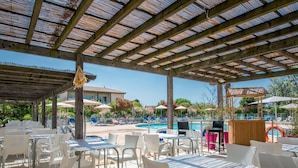 An outdoor patio area with tables and chairs, a pool, and umbrellas. - Sowell Résidence Les Sablons by Interhome (Le Grau du Roi)