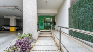 A modern hotel entrance with a green wall, a staircase, and a parking area. - Sky Stays at Agora Villamorra (Asunción)