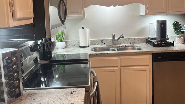 A modern kitchen with white cabinets, a stainless steel range, a built-in microwave, a coffee maker, and a sink. - NEW! Charming 2-bedroom townhome in convenient location (North Charleston)