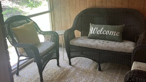 A porch with wicker furniture, a welcome sign, and a view of greenery. - NEW! Charming 2-bedroom townhome in convenient location (North Charleston)