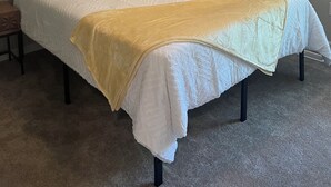 A neatly made bed with a white comforter, a yellow throw blanket, and several pillows. A ceiling fan with a light fixture is above the bed. - NEW! Charming 2-bedroom townhome in convenient location (North Charleston)