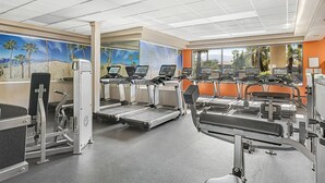 Une salle de sport équipée de tapis de course, de vélos d’appartement et d’appareils de musculation.
