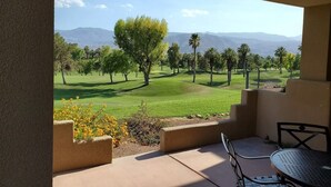 Une terrasse avec vue sur un terrain de golf et les montagnes.