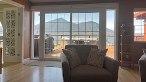 Ein Wohnzimmer mit einer großen Schiebetür, die auf einen Balkon mit Blick auf die Berge führt.