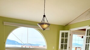 Ein Schlafzimmer mit großem Fenster, einem Bett, einer Couch und einer Pendelleuchte.