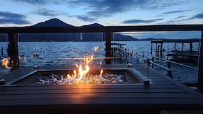 A deck with a fire feature, overlooking a body of water and distant mountains. - Lakefront Home with Amazing Views, Private Dock, Kayaks, Gameroom (Clearlake)