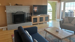 Ein Wohnzimmer mit Kamin aus Stein, einem Fernseher, einer Couch und einem Couchtisch.