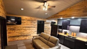A modern interior with a sofa, a dining table, and a kitchen area. - Couples Wilderness Suite (Cook)