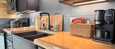 Una cocina moderna con armarios oscuros, electrodomésticos de acero inoxidable y encimera de madera.