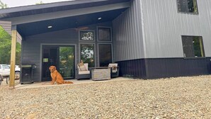 A modern house with a covered patio, a dog, and outdoor furniture. - Couples Wilderness Suite (Cook)