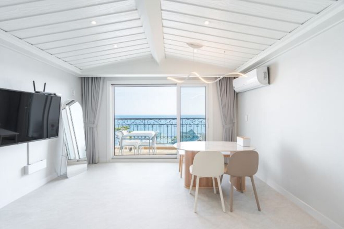 A modern room with a balcony, a dining area, and a TV.