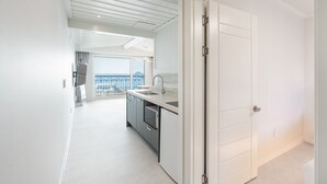 A modern kitchen with a view to the balcony, white walls, and a door leading to another room. - Ocean The Hill (Taean)
