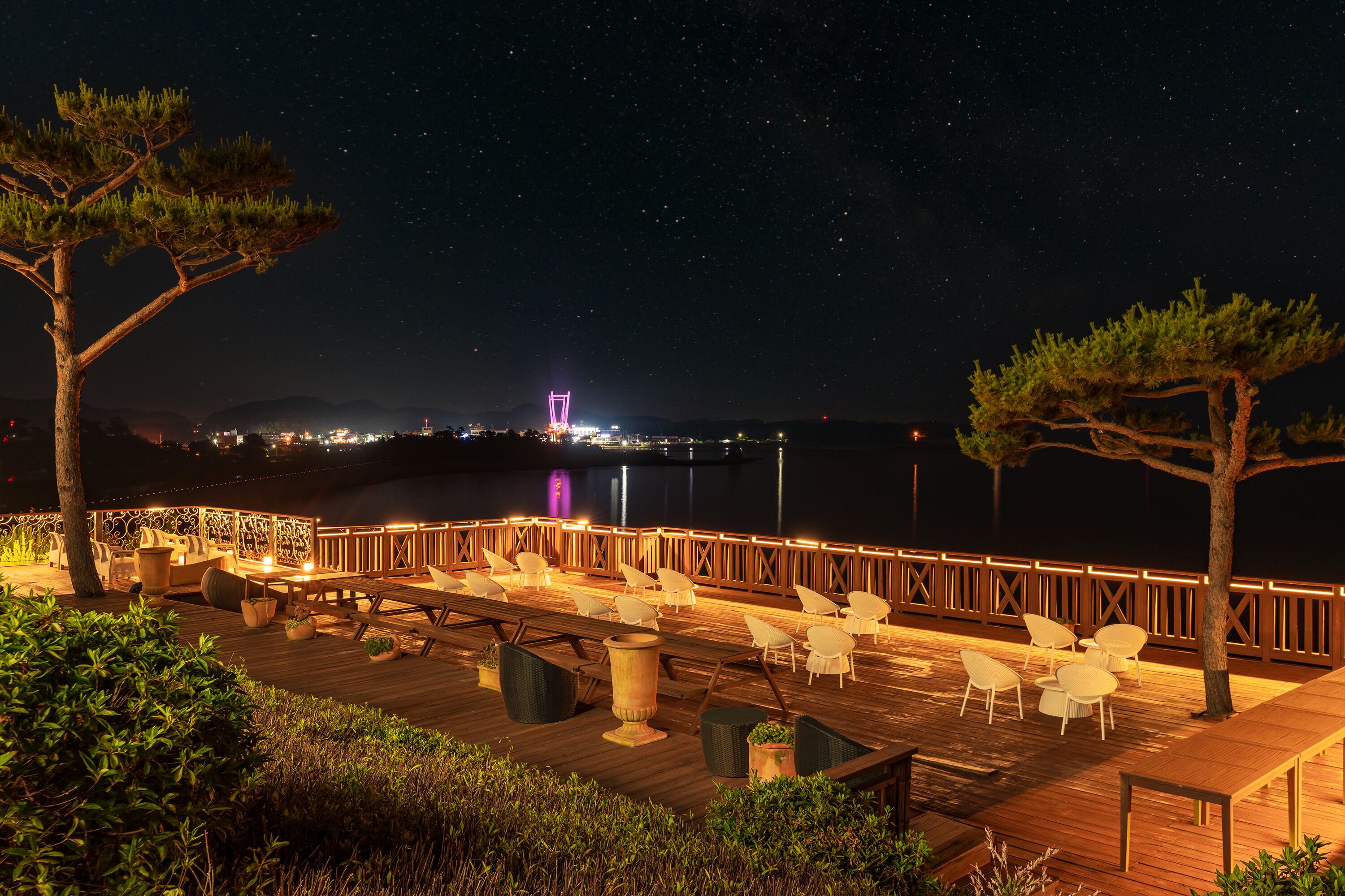 Une terrasse avec des sièges extérieurs, une rambarde en bois et une vue sur le ciel nocturne.