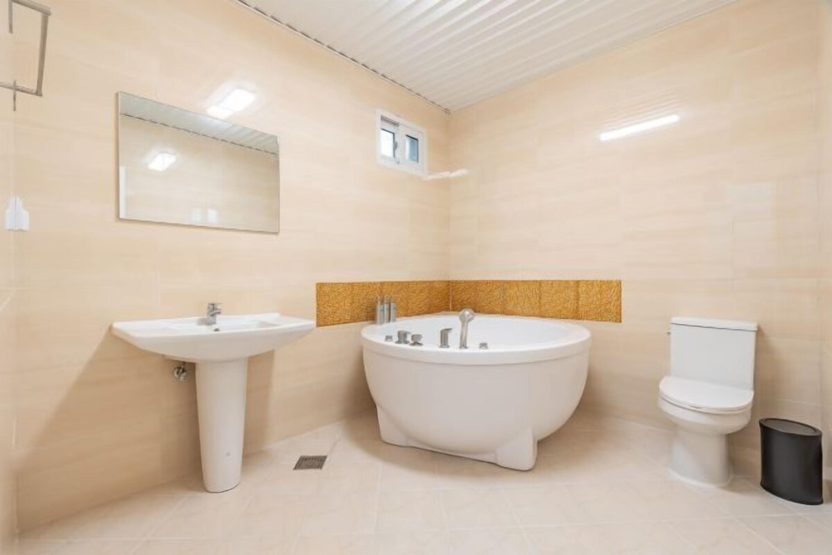 A modern bathroom with a pedestal sink, freestanding bathtub, and toilet.