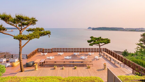 A wooden deck with outdoor seating and a view of the sea. - Ocean The Hill (Taean)