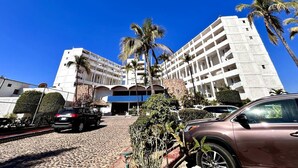 Un hôtel à plusieurs étages doté d’un atrium central, de palmiers et d’un espace de stationnement.