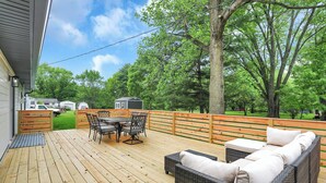 An outdoor deck with a wooden floor, a dining table with chairs, and a wicker sofa. - Zest of Zionsville with WiFi, AC (Zionsville)
