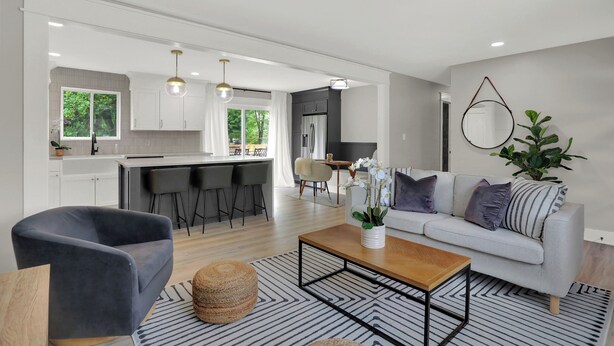 A modern living room with a grey sofa, a coffee table, and a dining area with a table and chairs. - Zest of Zionsville with WiFi, AC (Zionsville)
