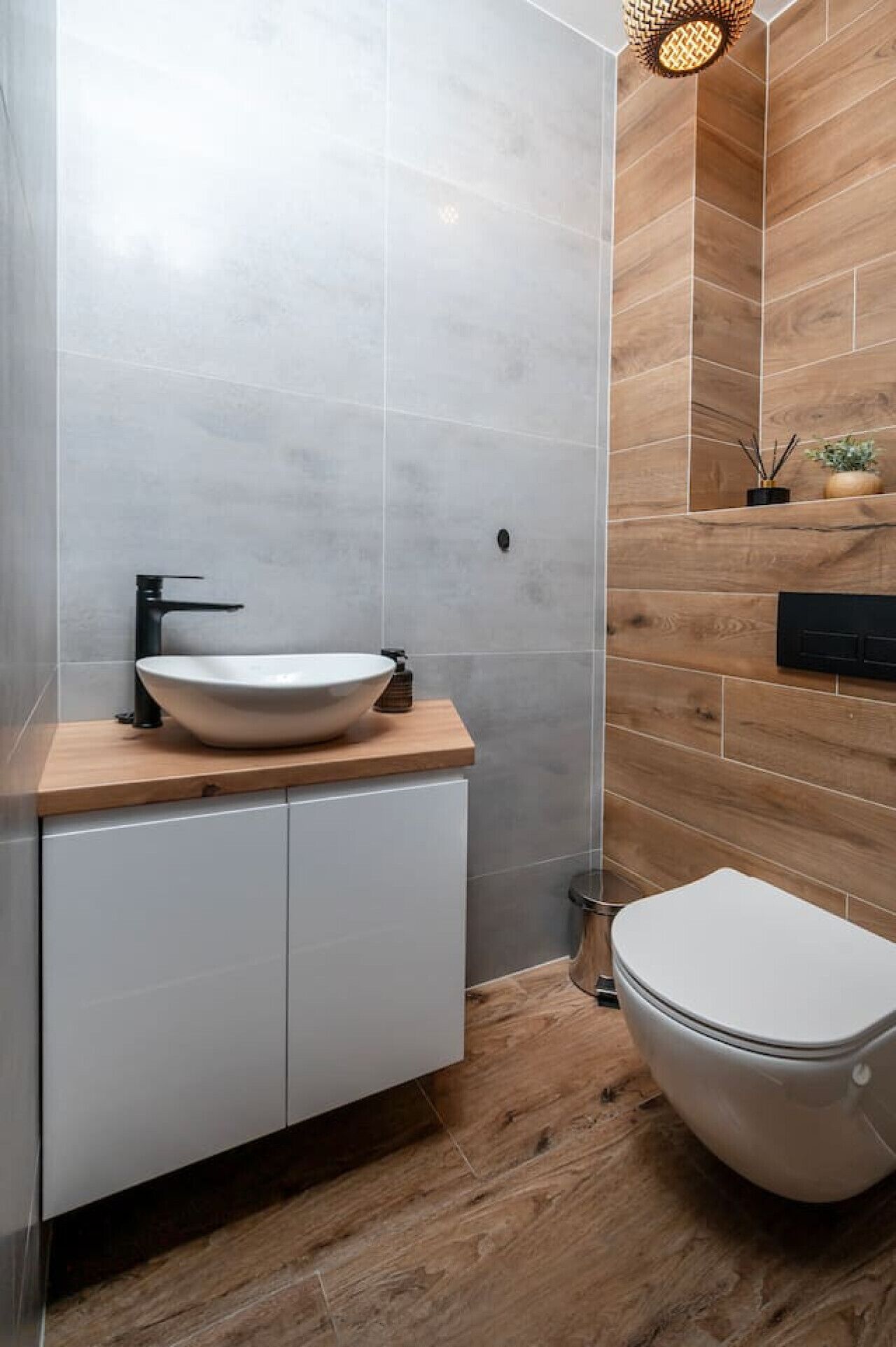 Un baño moderno con un lavabo blanco, un grifo negro y un mueble de tocador de madera.