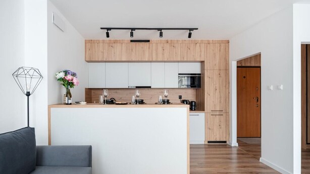 Una cocina moderna con una isla central, armarios blancos y detalles de madera.