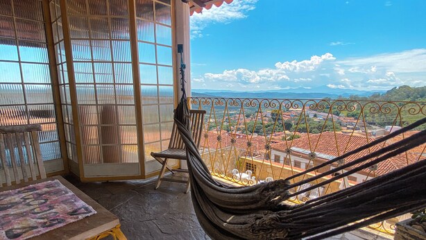 Una cadira espanyola a un balcó amb vista a una vila i muntanyes.