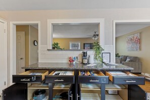 Una cocina moderna con encimera de granito, cajones negros y ventilador de techo.