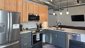 Une cuisine moderne dotée d’appareils électroménagers en acier inoxydable, de meubles en bois et d’un éclairage suspendu.