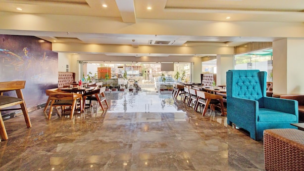 Een ruime hotel lobby met een gepolijste marmeren vloer, houten meubels en een grote blauwe fauteuil.