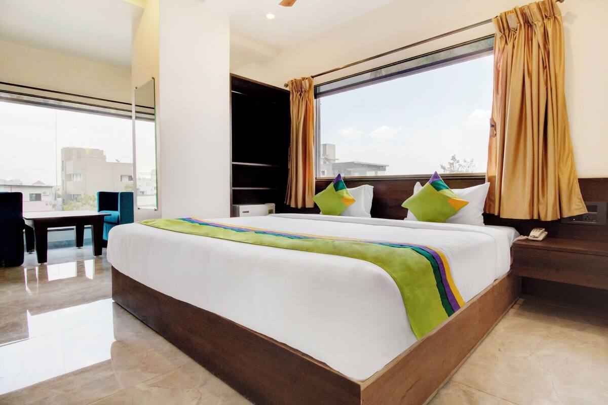 Habitación de hotel con una cama grande, un escritorio y una ventana con cortinas.