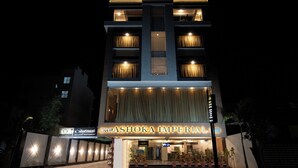 Een hotel met een moderne gevel, grote ramen en een bord met 'Hotel Ashoka Imperial'.