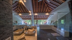 Una moderna spa con soffitto in legno, pareti in pietra e una vasca da bagno ampia.