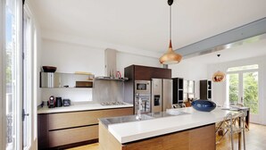 Una cocina moderna con una isla central, electrodomésticos de acero inoxidable y un amplio ventanal que proporciona luz natural.