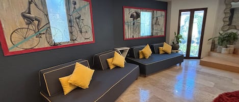 A modern living room with a dark-colored sofa set, yellow cushions, and two large wall-mounted paintings of bicycles.
