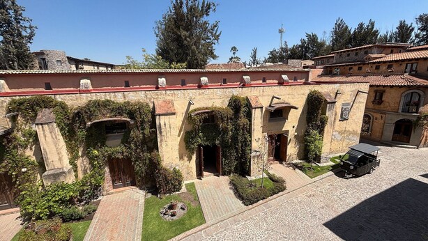 Un patio con edificios de piedra, arcos y un área pavimentada con un vehículo.